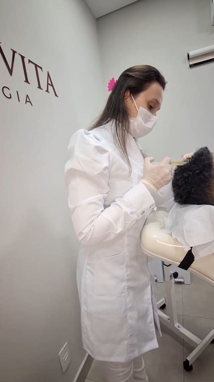 Gabriella aplicando o protocolo no couro cabeludo de uma paciente, na clínica Cordis Vita
